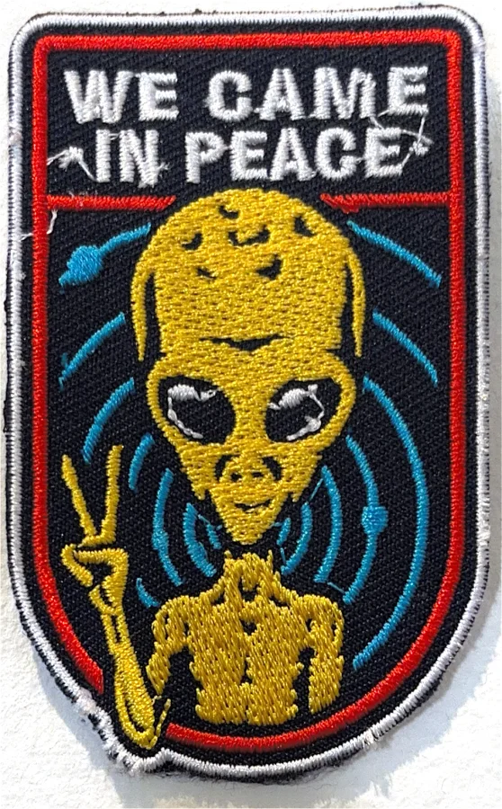 A patch of an alien flashing a peace sign: We came in peace